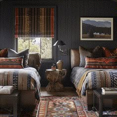 two beds in a room with black walls and rugs on the floor, one has a wooden end table