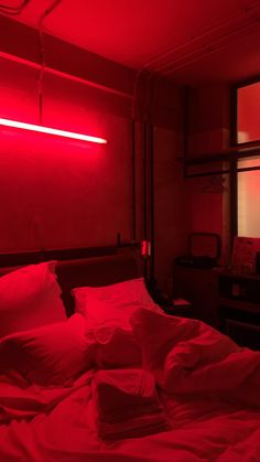 a bed in a room with red light coming from the ceiling and pillows on it