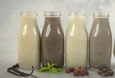 four glass bottles filled with different types of milk