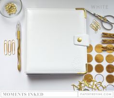 the contents of a white planner spread out on a table with gold foil and scissors