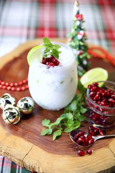 a wooden platter topped with a drink and garnished with pomegranates