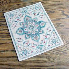 a white and blue rug sitting on top of a wooden floor next to a phone