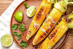 grilled corn on the cob with limes and seasoning next to it