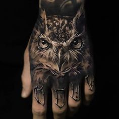 an owl tattoo on the palm of a person's hand, which is covered in black and grey ink