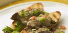 two pieces of bread with meat and vegetables on it sitting on a plate next to a fork