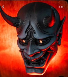 a black mask with red eyes and horns on it's face is lit up