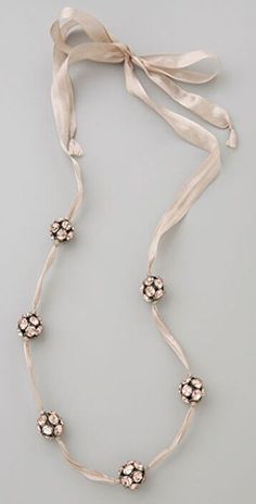 a necklace with flowers on it and a ribbon tied around the neck, hanging from a gray background