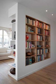 a living room filled with furniture and bookshelves next to a white couch in front of a window