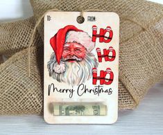 a christmas tag with a santa clause on it and money in front of the tag