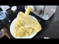 a white plate topped with pasta next to a blender