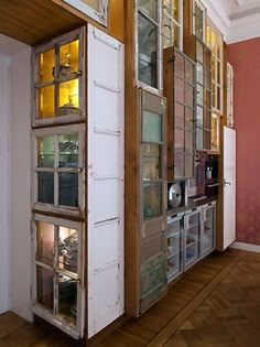 an old refrigerator with glass doors is in the middle of a wood floored room