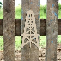 a wooden cutout of a tower on a fence post with grass in the background