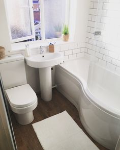 a bathroom with a toilet, sink and bathtub next to a window in it