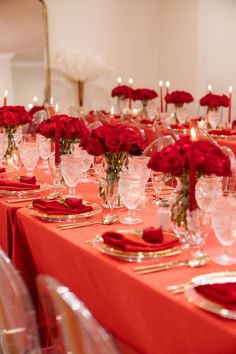 a long table is set with red roses and place settings for the guests to sit at