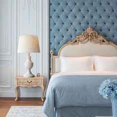 a bedroom with blue upholstered headboard and white bedding