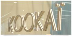 the word kodak is reflected in a glass window with an open door behind it