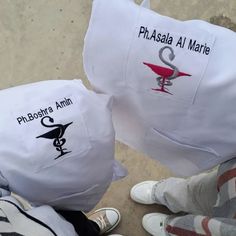 two white pillows with logos on them sitting next to someone's feet and shoes