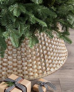 two wrapped presents under a christmas tree in front of a wicker basket with ribbon