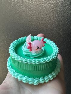 a hand holding a small toy in the shape of a cake