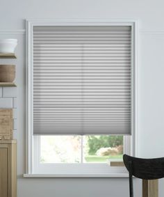 a kitchen window with blinds in it and a chair next to the window sill