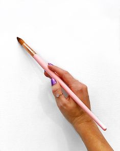 a hand holding a pink and brown pencil