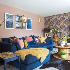 a living room with blue couches and pictures on the wall above them, including sunflowers