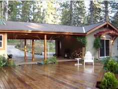 a wooden deck in front of a house with a white lawn chair on top of it