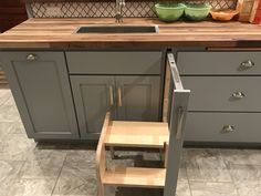 a kitchen with gray cabinets and wooden steps