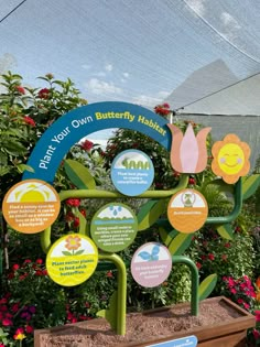 the butterfly habitat has many different signs on it's posts and is surrounded by flowers