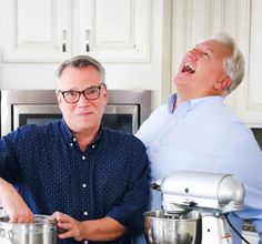 two men laughing in the kitchen with pots and mixers