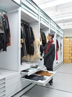 a woman looking at clothes in a closet