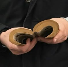 a person holding two pieces of brown paper in their hands, with the end rolled up