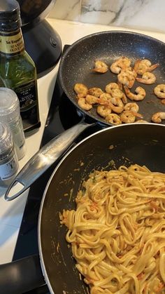 shrimp and pasta being cooked in a skillet on the stove top with other ingredients