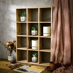 a wooden shelf filled with potted plants next to a window