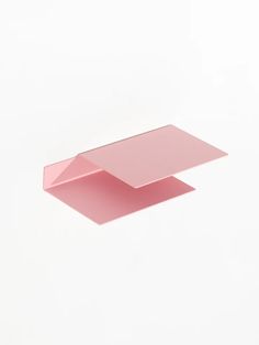 a pink object floating in the air on top of a white surface with no one around it