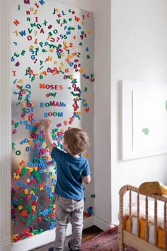 a little boy standing in front of a wall with letters on it