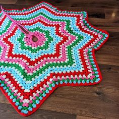 a crocheted star is on the floor next to a pair of pink scissors