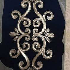 the back of a black jacket with silver sequins on it and an intricate design