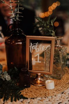 a table topped with a brown bottle and a wooden sign that says table 1 on it