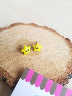 two little yellow stars sitting on top of a piece of wood next to a card