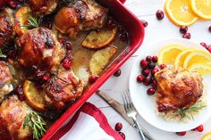 a red casserole dish filled with chicken, potatoes and cranberries