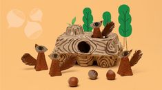 an animal house made out of wood with birds and acorns on the ground