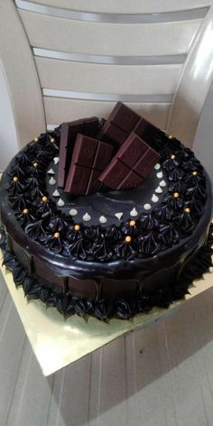 a chocolate cake sitting on top of a wooden table next to a white plastic chair