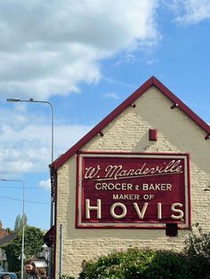 a sign for a bakery called hoviss on the side of a building with people walking by