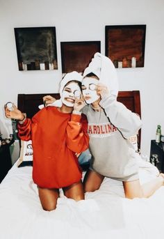 two people with face masks on sitting on a bed