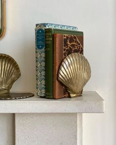 two books are sitting on a shelf next to a bookend with a gold shell