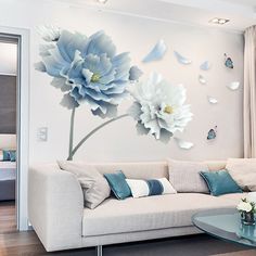 a living room with white furniture and blue flowers on the wall, butterflies flying around