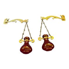 pair of red and gold earrings hanging from hooks on white background with clippings