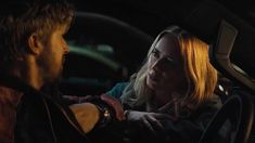 a man and woman sitting in the drivers seat of a car looking at each other