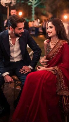 a man sitting next to a woman in a red dress